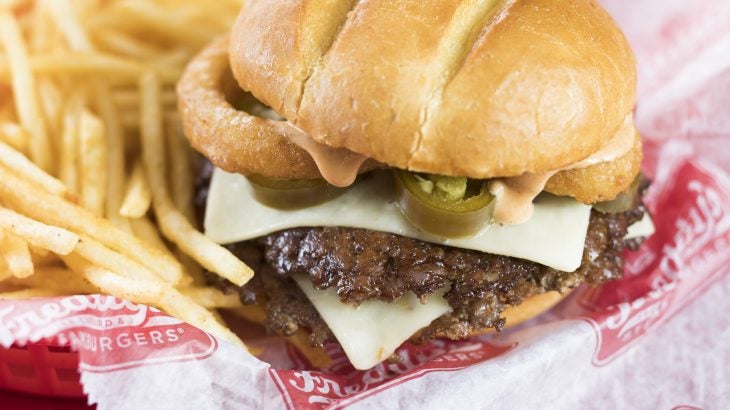 Jalapeno Pepper Jack Steakburger at Freddy's Frozen Custard & Steakburgers comes with two steakbuger patties topped with pepper jack cheese, grilled jalapenos, and two onion rings. All on a homestyle bun.